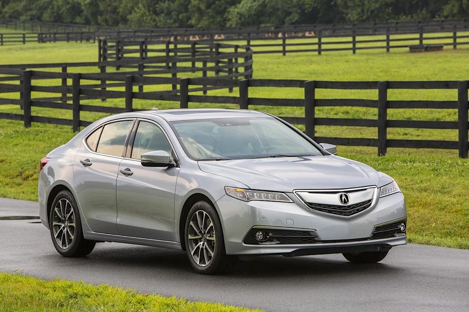 An Acura TLX ion front of a long, winding fence.
