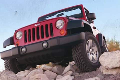 A red Wrangler climbing over rocks