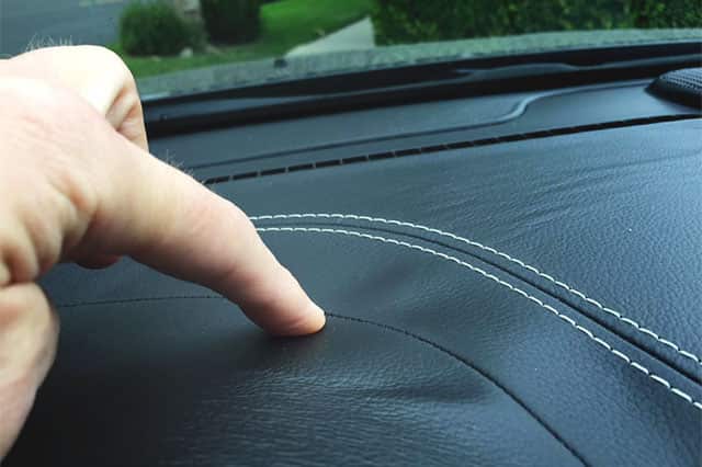 A finger pointing to the wrinkles in a black dashboard