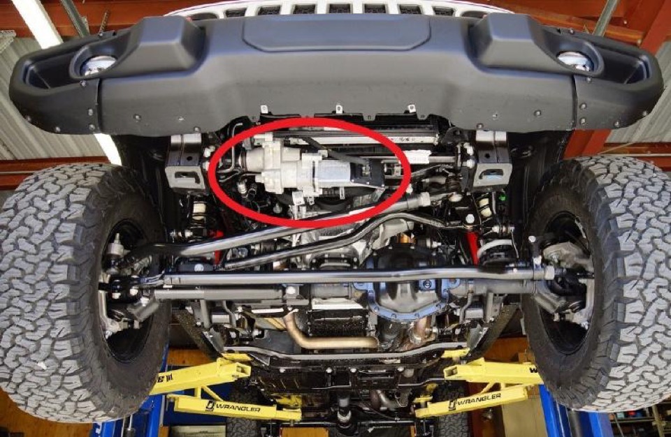 A red circle highlights the sway bar disconnect system on the bottom front of a Jeep hoisted up on lifts.