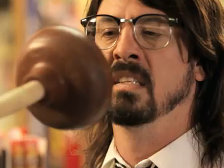 Dave Grohl making a yucky facial expression as a plunger gets closer to his face