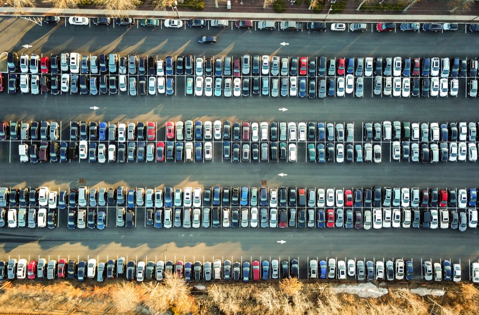 An overhead view of a parking lot with cars neatly lined up inside parking spaces.