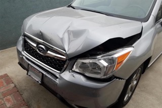 Smashed front hood of a gray Subaru