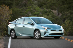 A pale blue Prius parked sideways on a road