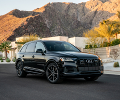 A black Q7 parked on a street with glowing mountains in the background.