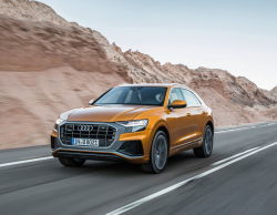 An orange Audi SUV driving down the road