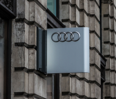 Gray sign with the Audi logo hanging from the side of a building