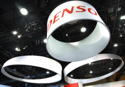 A circular sign with the DENSO logo, hanging from a ceiling