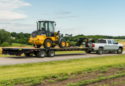 A truck towing a tractor on a trailer