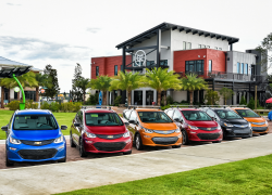 A line of colorful Bolt EVs all parked in front of a civic building