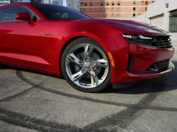 Closeup of a red Camaro over some tire burnout marks