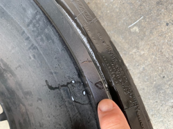 A finger points to a tiny crack on a Corvette rim