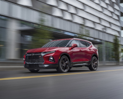 A red Chevy SUV over a blurry city background