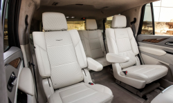 Looking back towards the second and third row seats of a GM SUV with white interior.