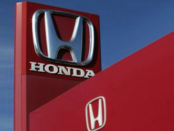 A Honda sign on a tower above a red building