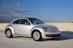 A gray Beetle driving in front of a beach