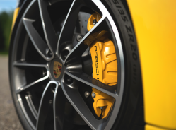 The wheel of a yellow Porsche, with the company's logo on the caliper cover.