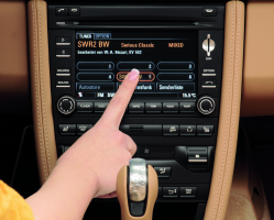A finger pressing an option on a giant infotainment touchscreen