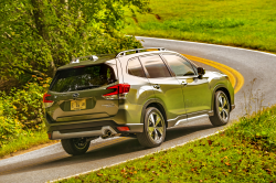 The back of a green Subaru wagon driving up a steep winding road